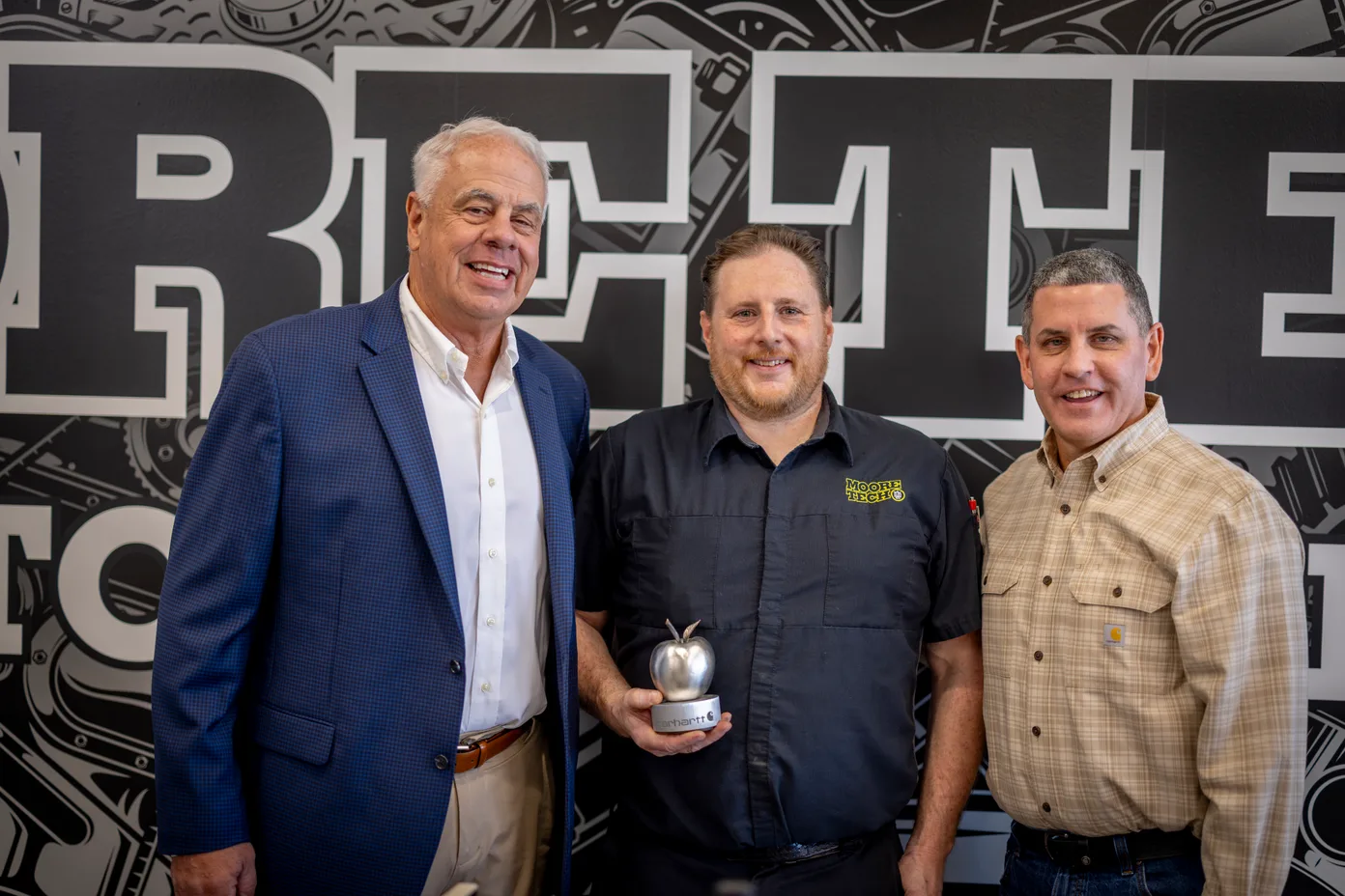 Paul Frye being presented the Steel Apple Award by a Moore Tech school official and Carhartt’s SVP of Supply Chain William Hardy